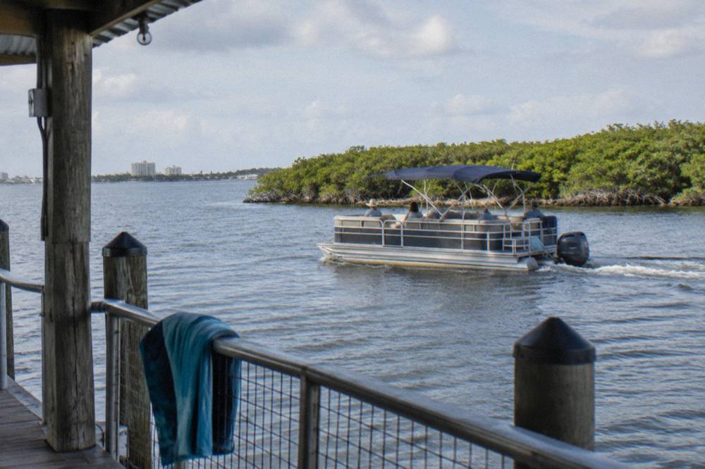 A covered passenger boat cruising past mangrove islands in the Banana River