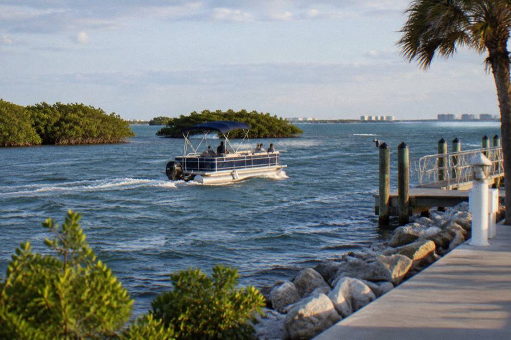 A pontoon dolphin tour boat cruising the open Banana River near mangrove shoreline