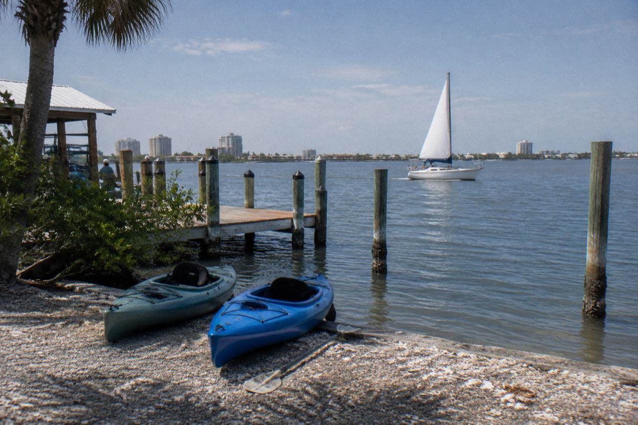 A small sailboat and kayaks on the calm Banana River near Cocoa Beach at midday