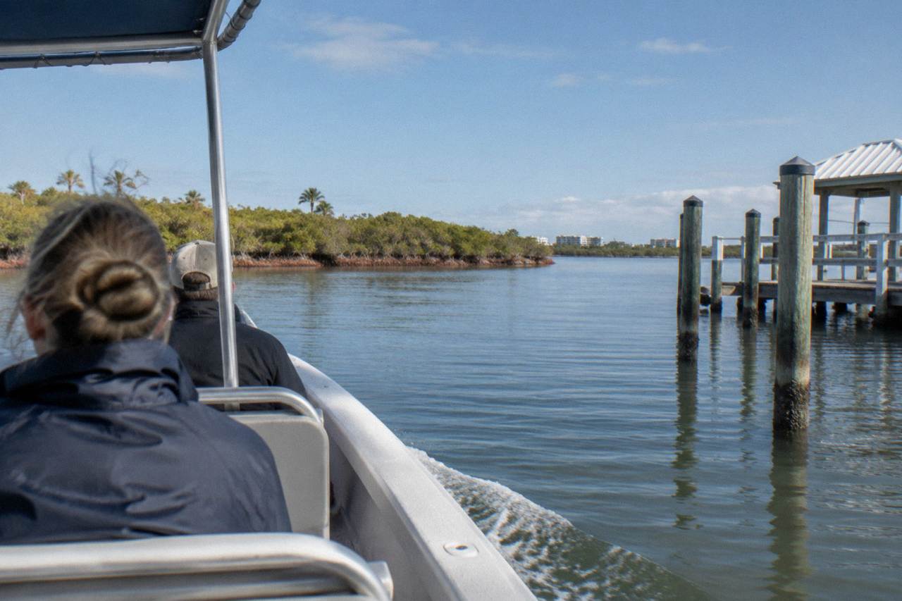 A small tour boat cruising calm lagoon water at Cocoa Beach with mangroves along the shoreline