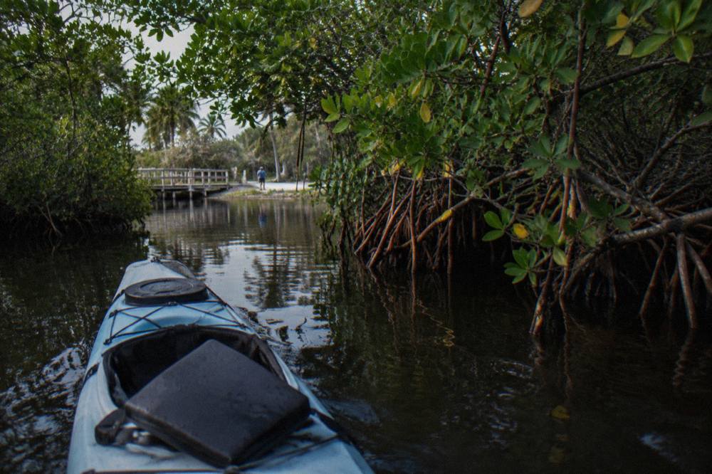 Sea kayak resting on dark lagoon water with a faint blue streak trailing from the hull