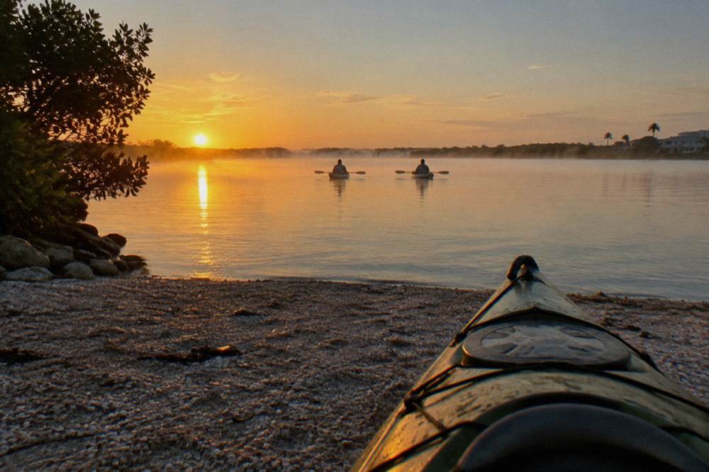 Kayaks drifting quietly on still lagoon water at sunrise