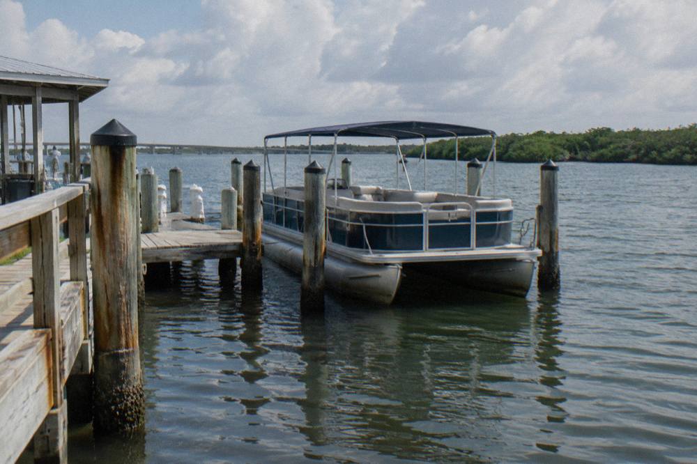 A boat dock on a calm lagoon at late afternoon with mangrove shoreline in the distance