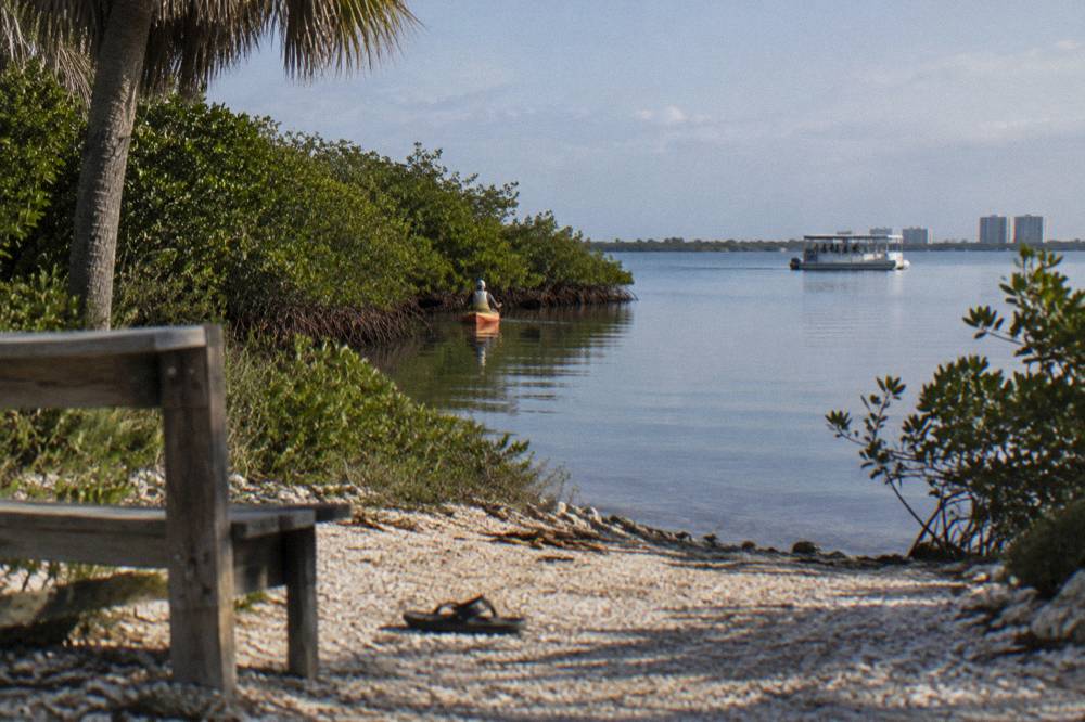 A small tour boat and a kayak on calm lagoon water at different distances from shore