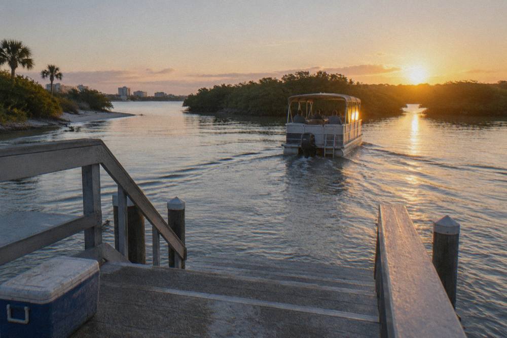 Small passenger boat crossing calm lagoon water in early morning light near mangrove islands