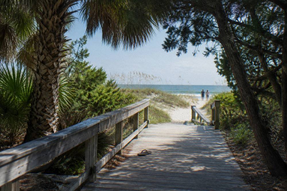 Boardwalk through coastal hammock leading toward calm ocean at a Cocoa Beach park