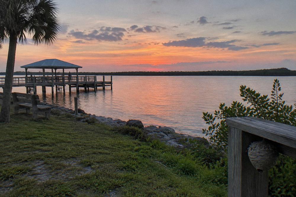 Wide view of the Banana River at dusk with silhouetted mangrove shoreline and calm water
