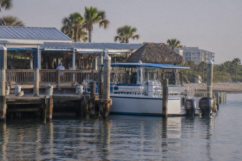 Tour boat docked beside a waterfront restaurant on a calm lagoon in Cocoa Beach