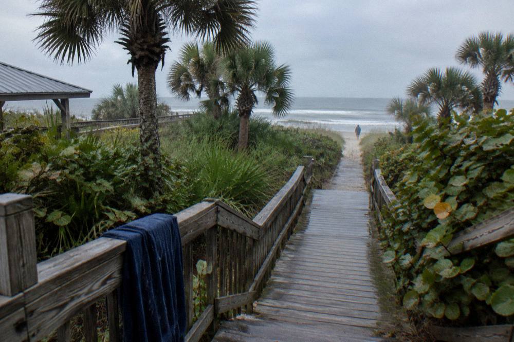 Boardwalk path through palm hammock leading toward a beach in Cocoa Beach