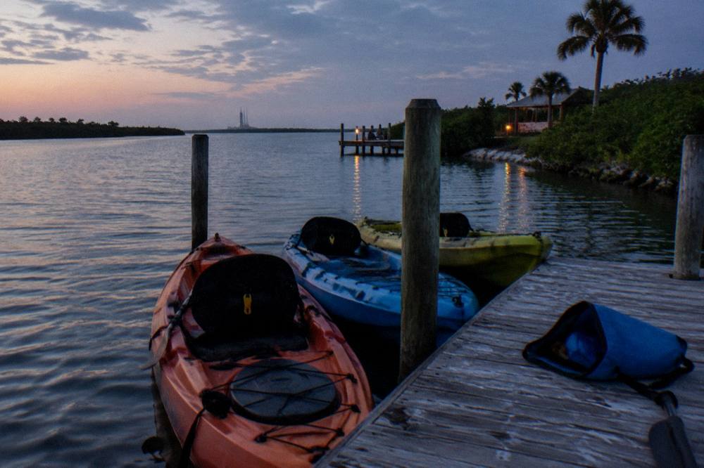Kayaks with headlamps gathered at a dock before a night paddle