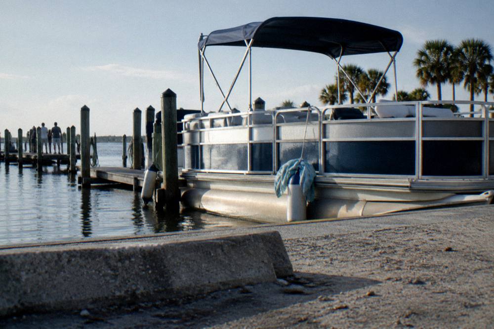 Waterfront parking lot beside a docked pontoon tour boat