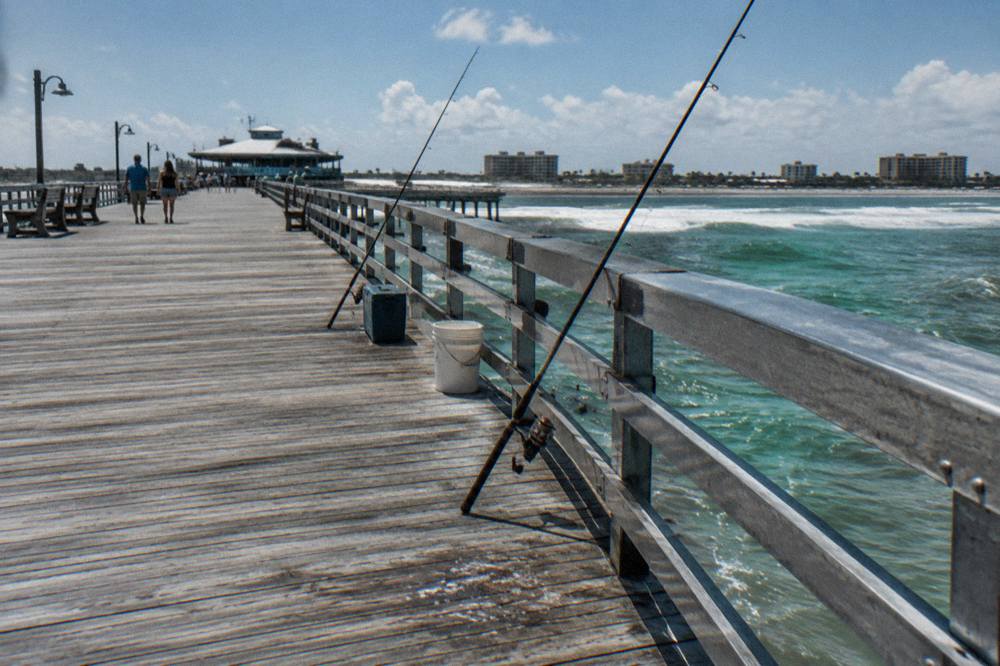 Long wooden pier stretching over green Atlantic surf toward the horizon
