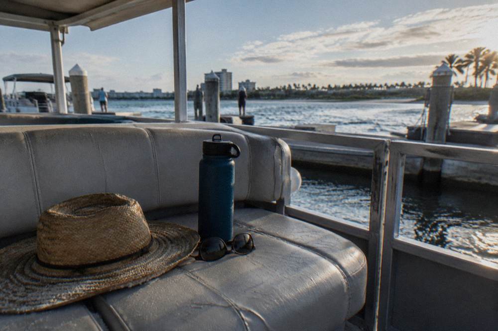 Sunglasses hat and water bottle resting on a boat bench seat